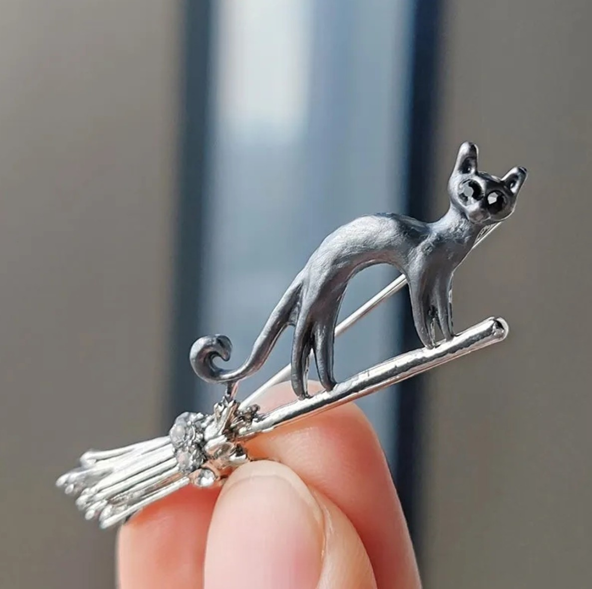 Eleganta piespraude ar melnu kaķi uz slotas, dekorēta ar mākslīgajiem dārgakmeņiem